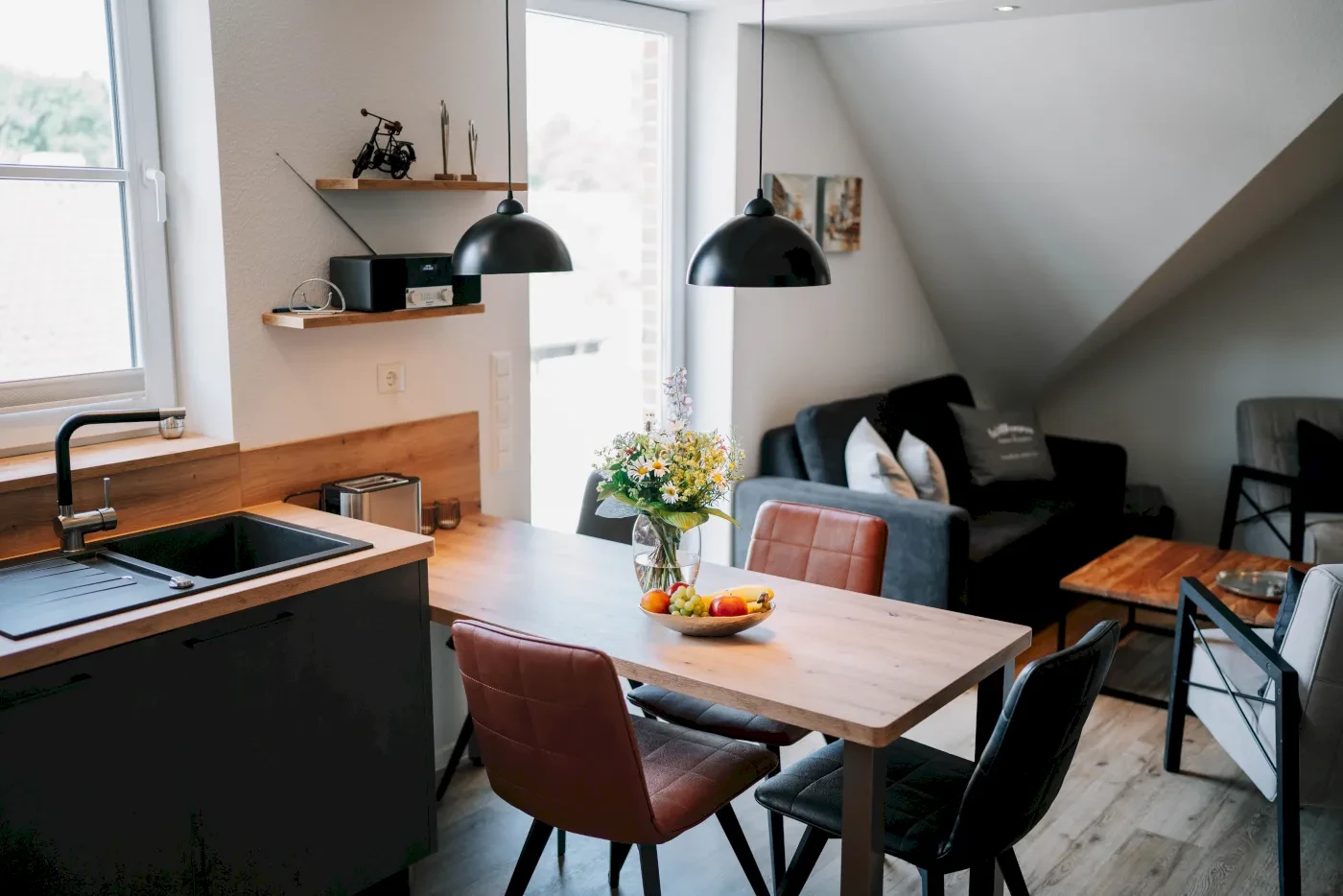 Ferienwohnung mit Fokus auf den Essstisch fotografiert aus der Küche mit Blick auf das Sofa.