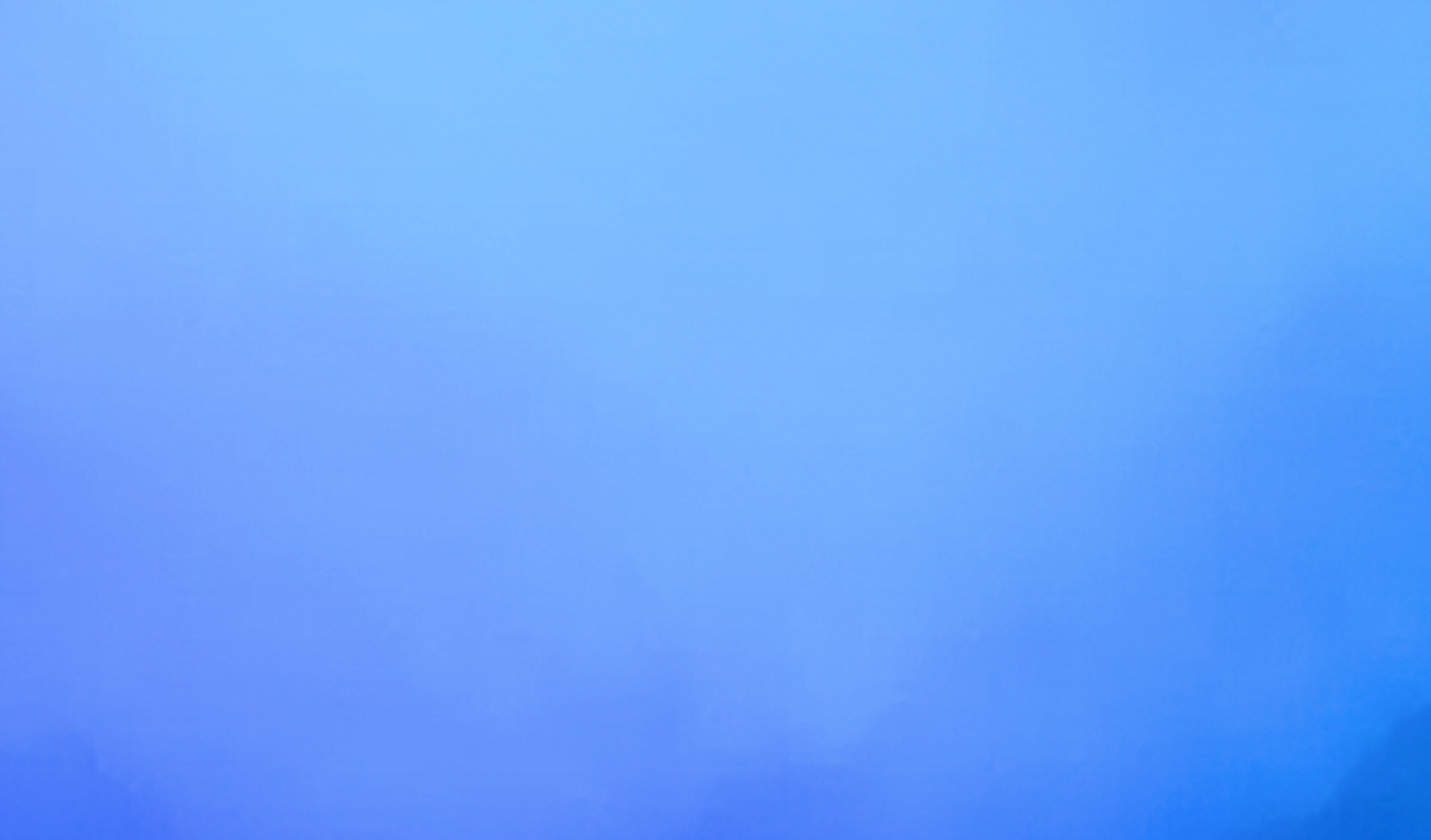 A plane flying through a blue sky filled with fluffy white clouds.