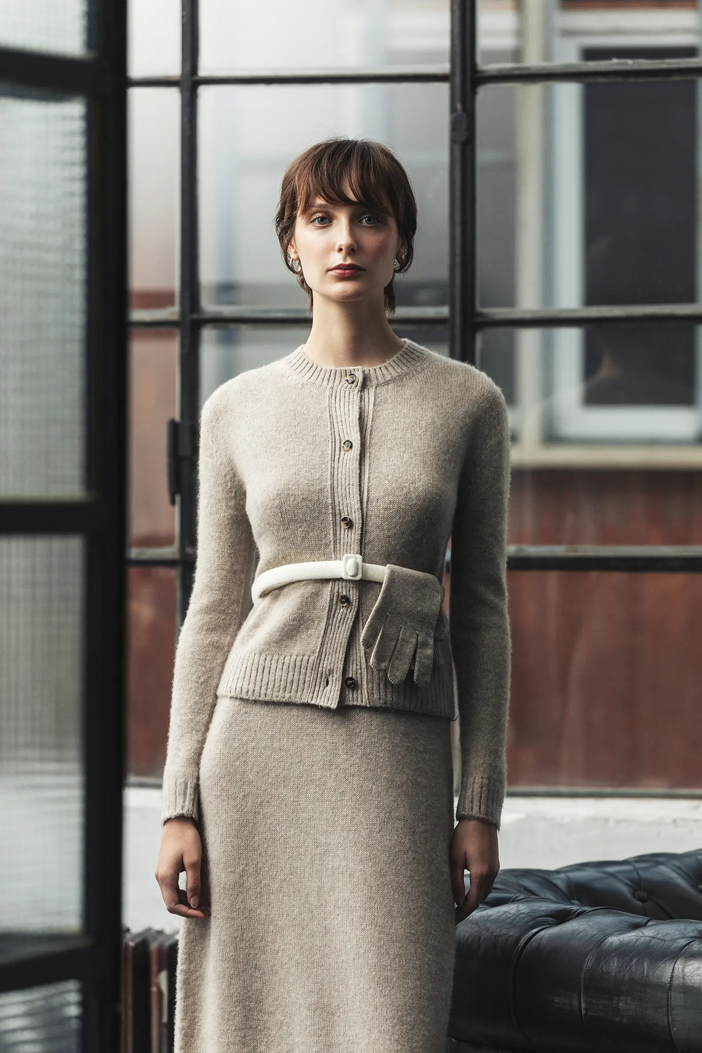 Woman in taupe cashmere cardigan with tonal skirt, belted at the waist with matching gloves – Aida Barni FW25/26 collection.