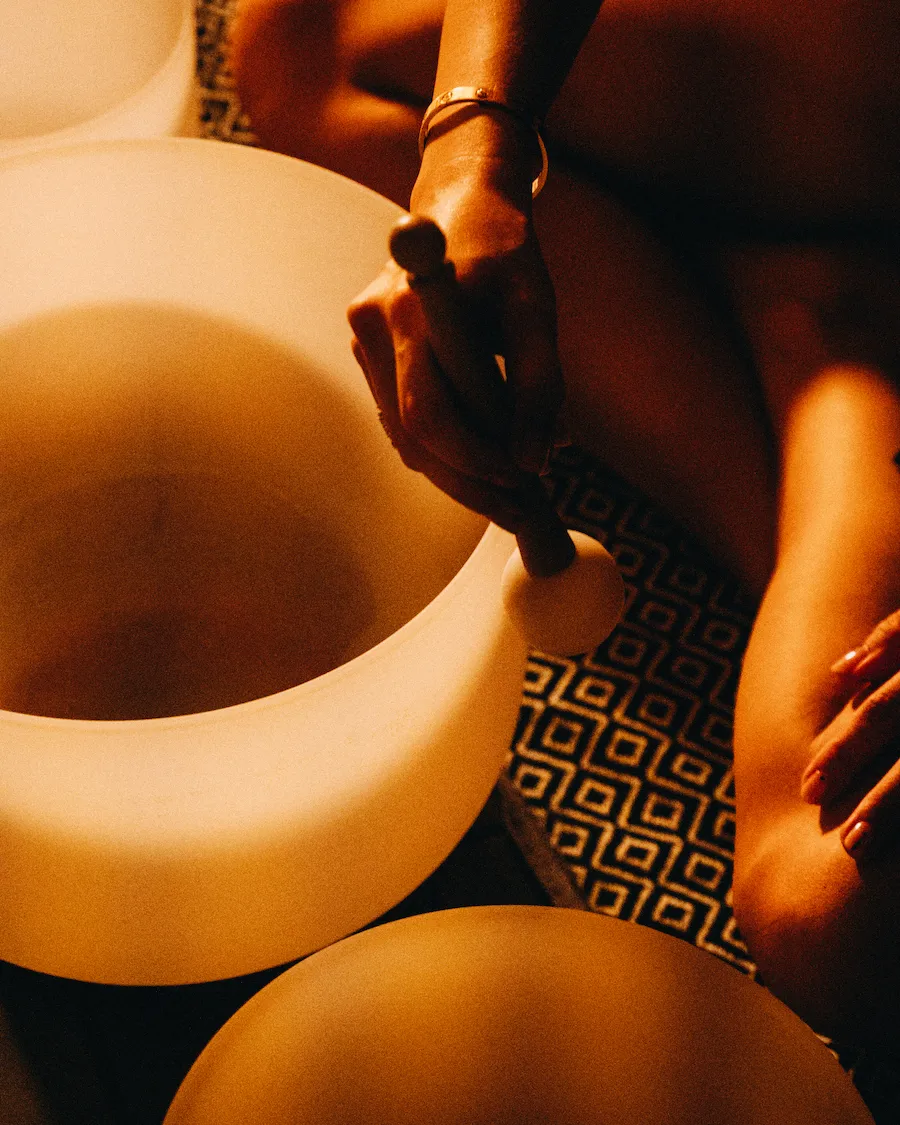 Hand gently playing a crystal singing bowl during a sound bath ritual in a Vancouver spa.