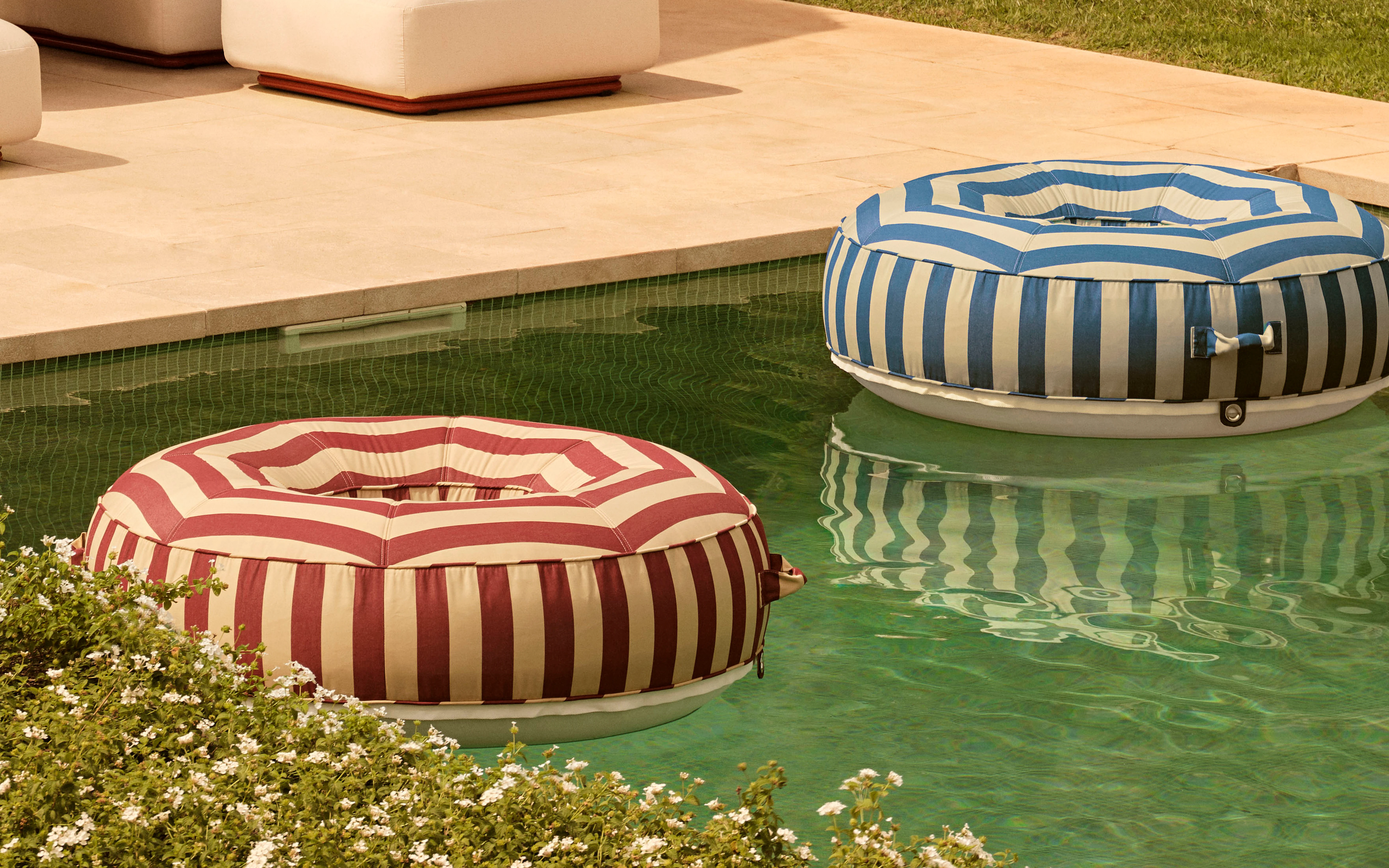 Pair of striped circular luxury pool floats in red and blue by Oliver James Lilos — floating elegance designed for adults in high-end pools