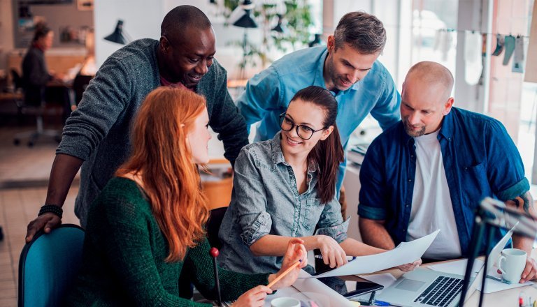 Equipe de marketing debatendo sobre pilha de documentos