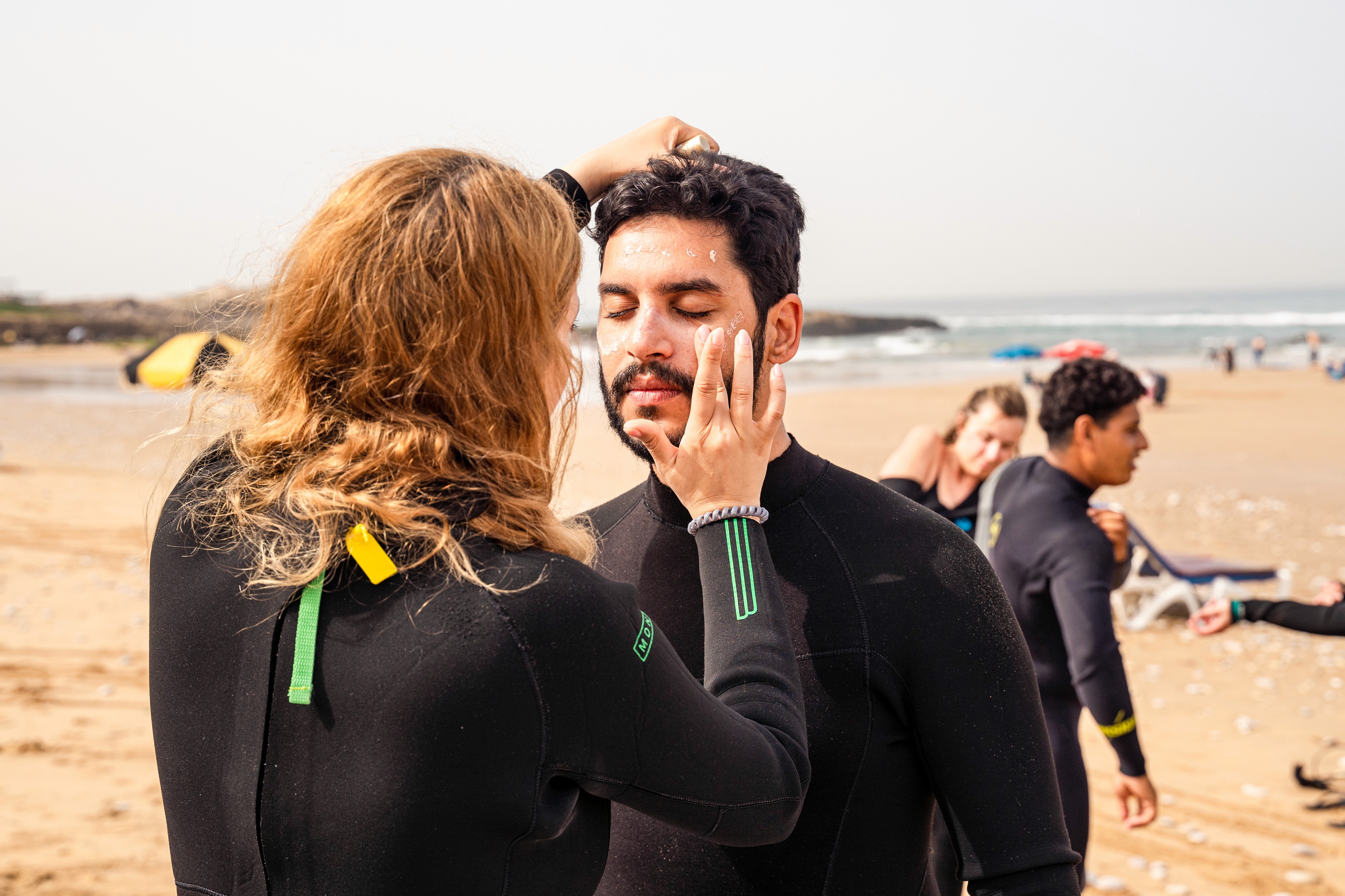 a group of people carrying surfboards on top of a beach