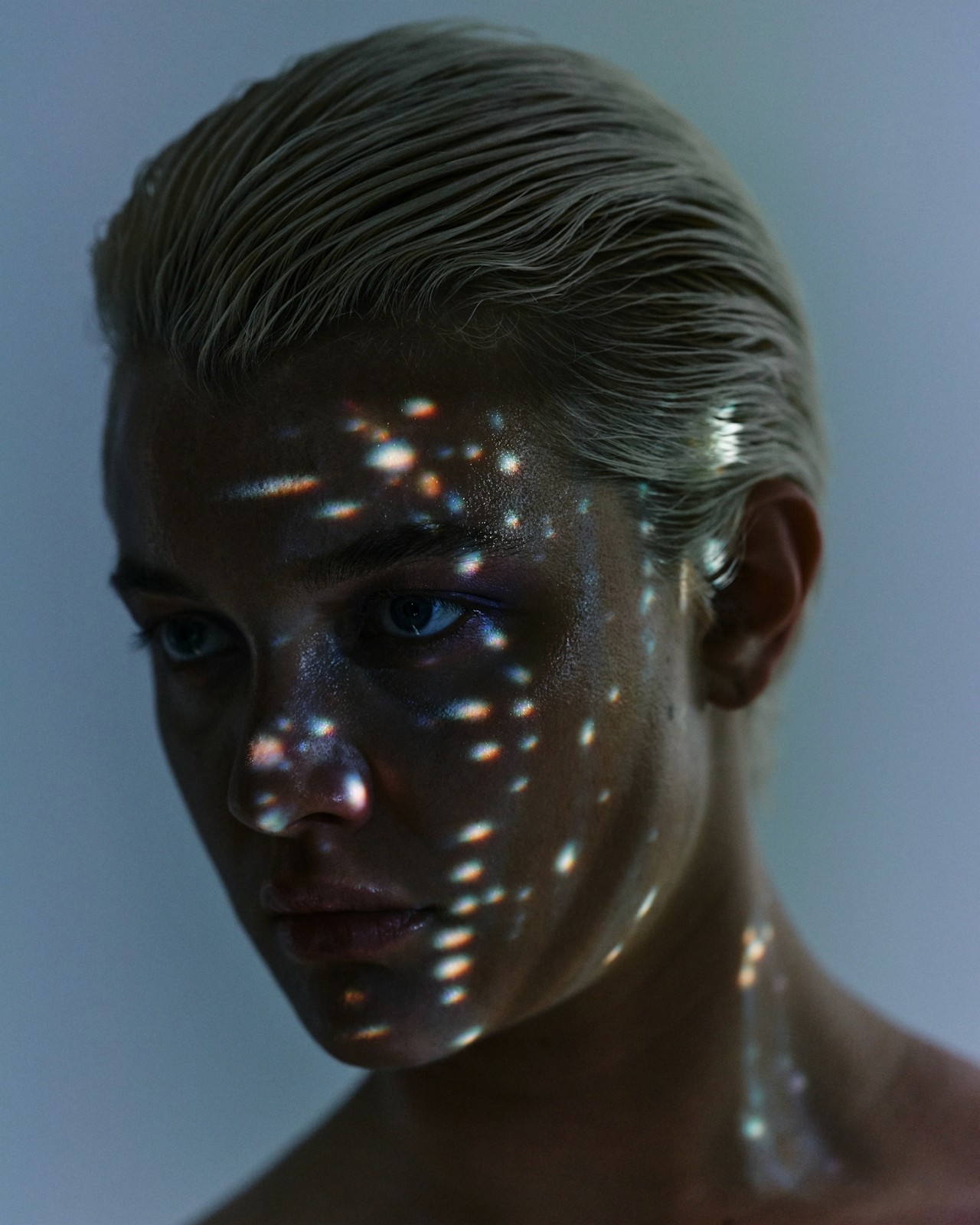 A softly lit portrait with scattered light reflections across the face.