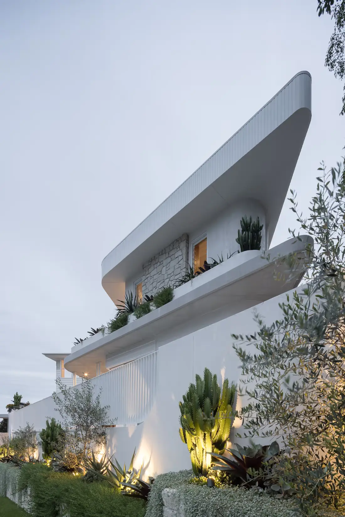 Clare House facade with lighting in the landscaping and a view of the curves