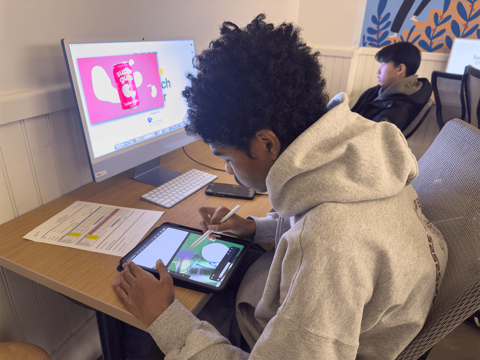 A teen participant works on his iPad on a design project.