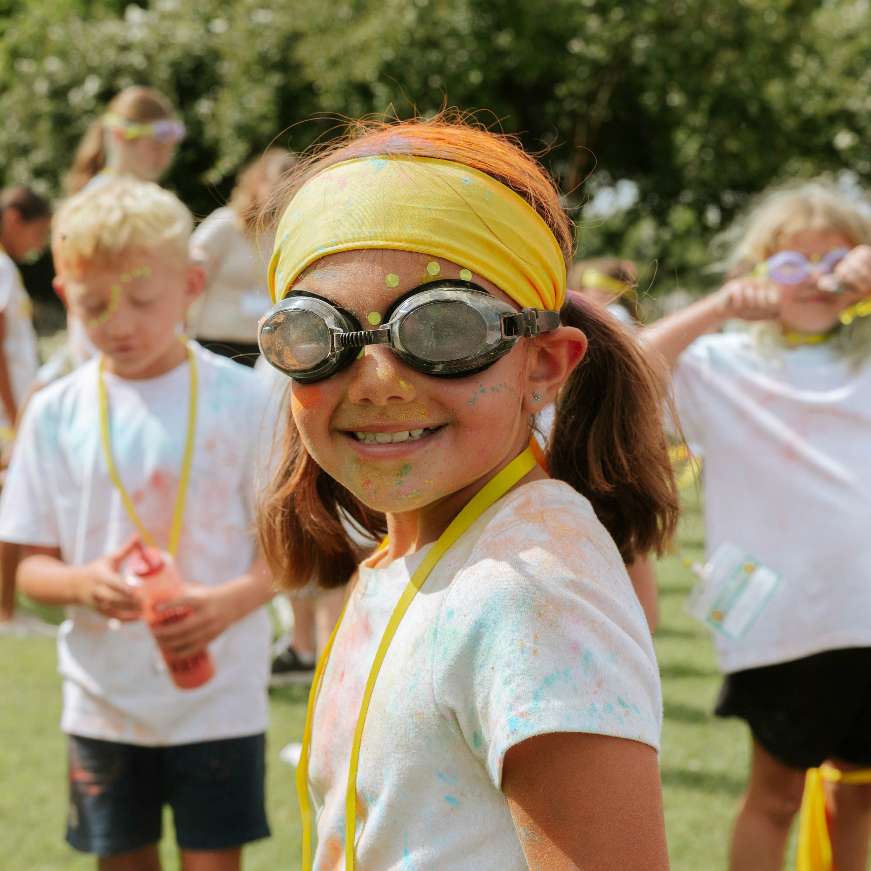 A young boy focused on writing at a table, with another child working in the background.