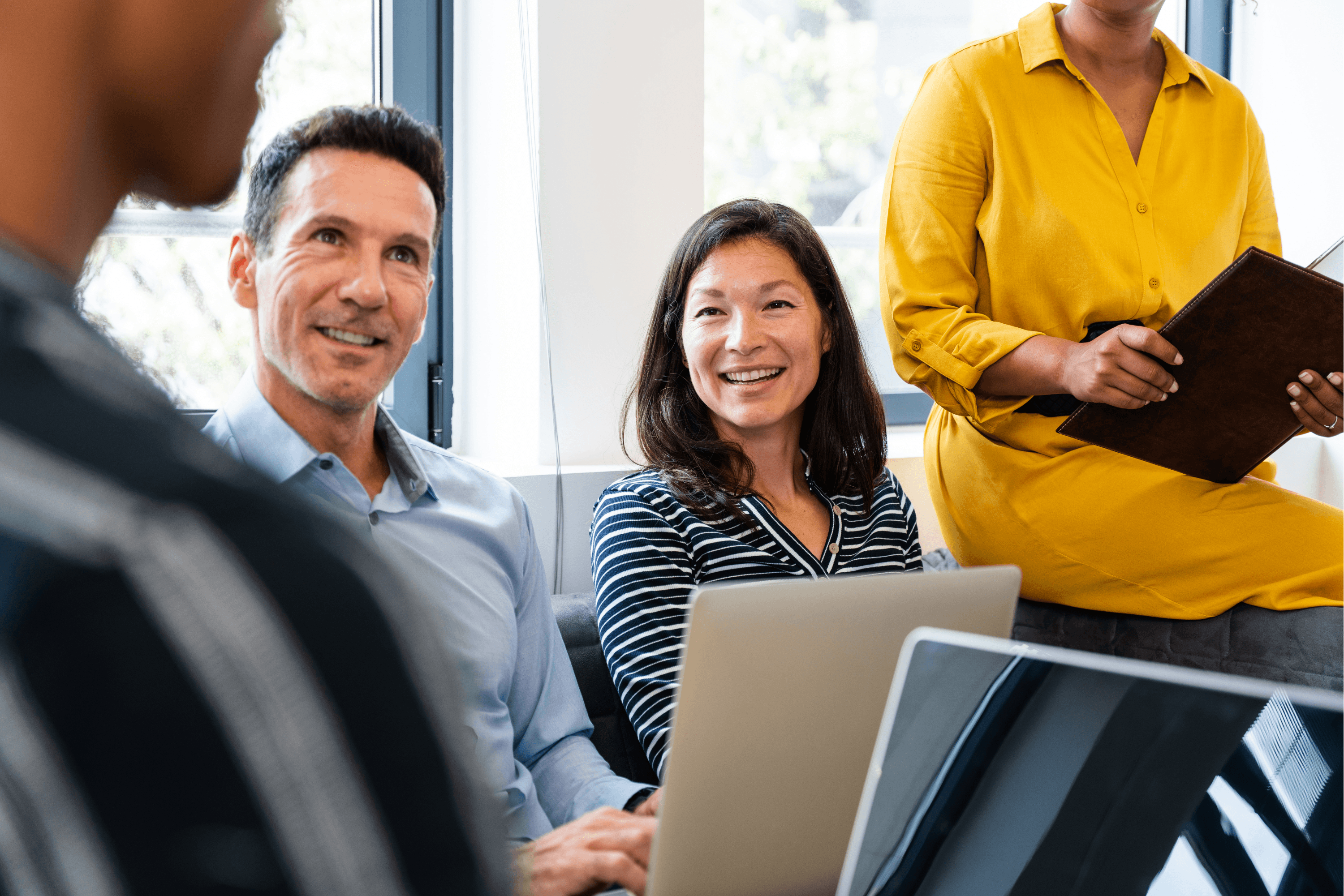 Two business women talking about sales in office at desk with laptop