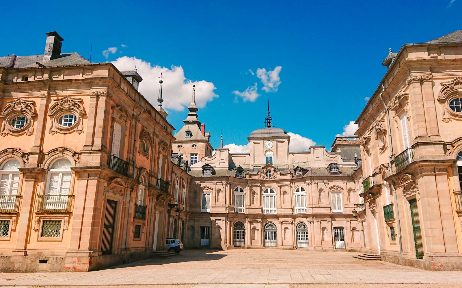 Dvorište kraljevske palače La Granja de San Ildefonso s raskošnom arhitekturom pod vedrim plavim nebom.