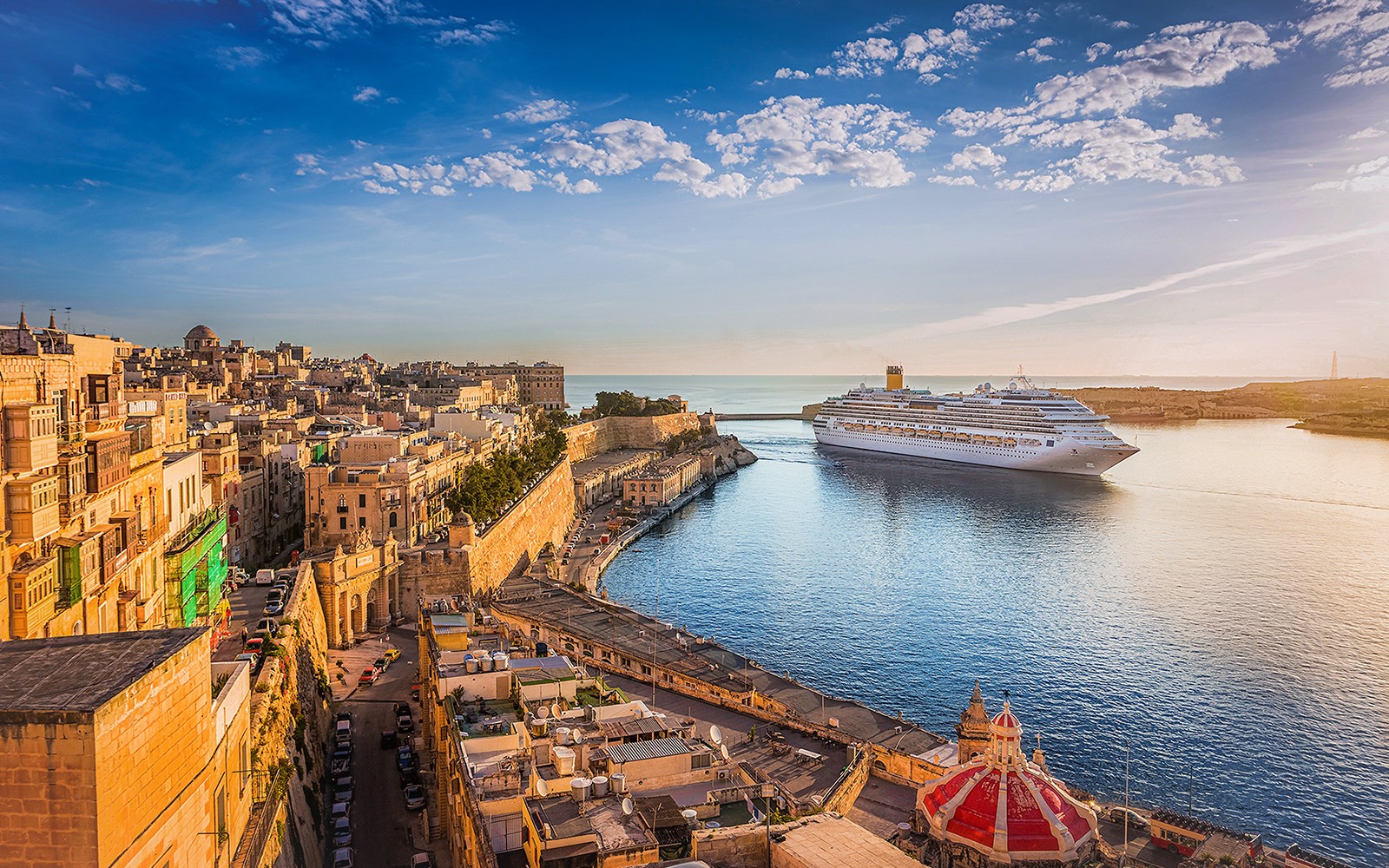 Cruise ship in Valletta harbor with historic cityscape, viewed from Sliema.