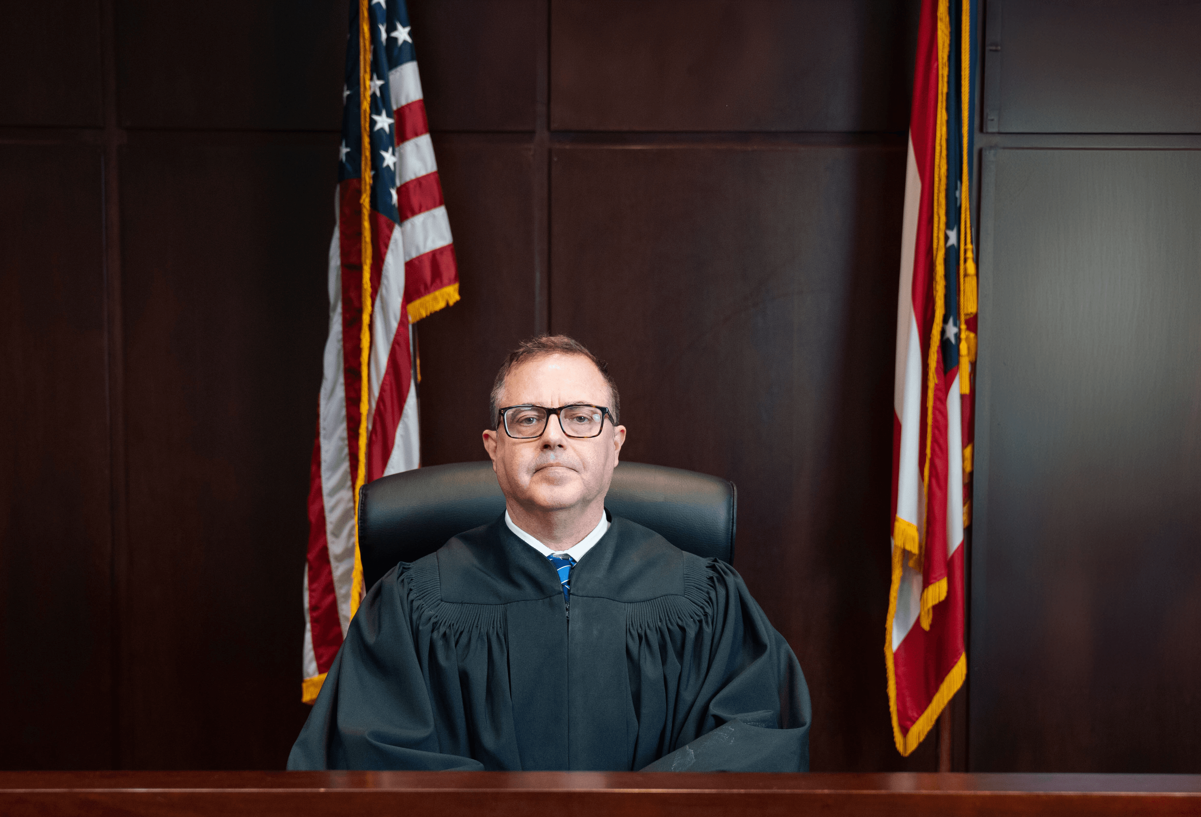Magistrate Steven M. Abshire seated on the bench in judicial robes beneath the Great Seal of Ohio