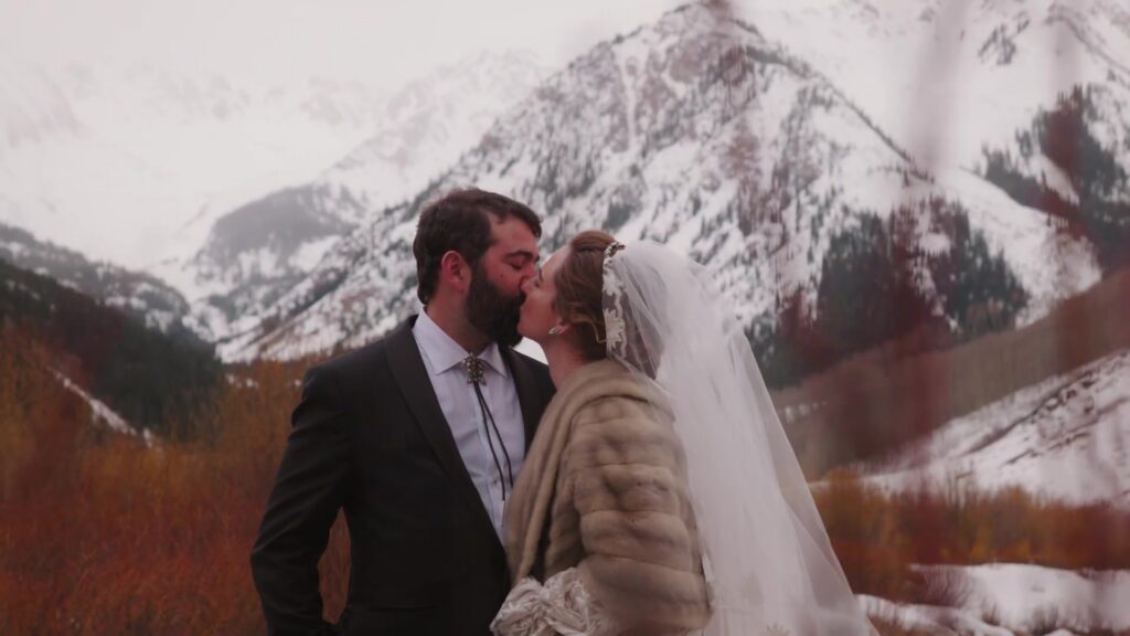 Rebecca and Javier kissing at Pine Creek Cookhouse Ashcroft with Elk Mountain Range in winter background