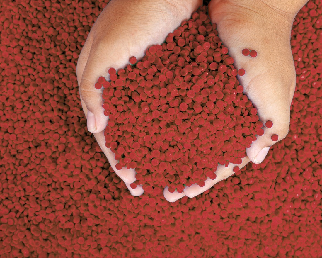 Close-up of hands holding blue plastic polymer granules