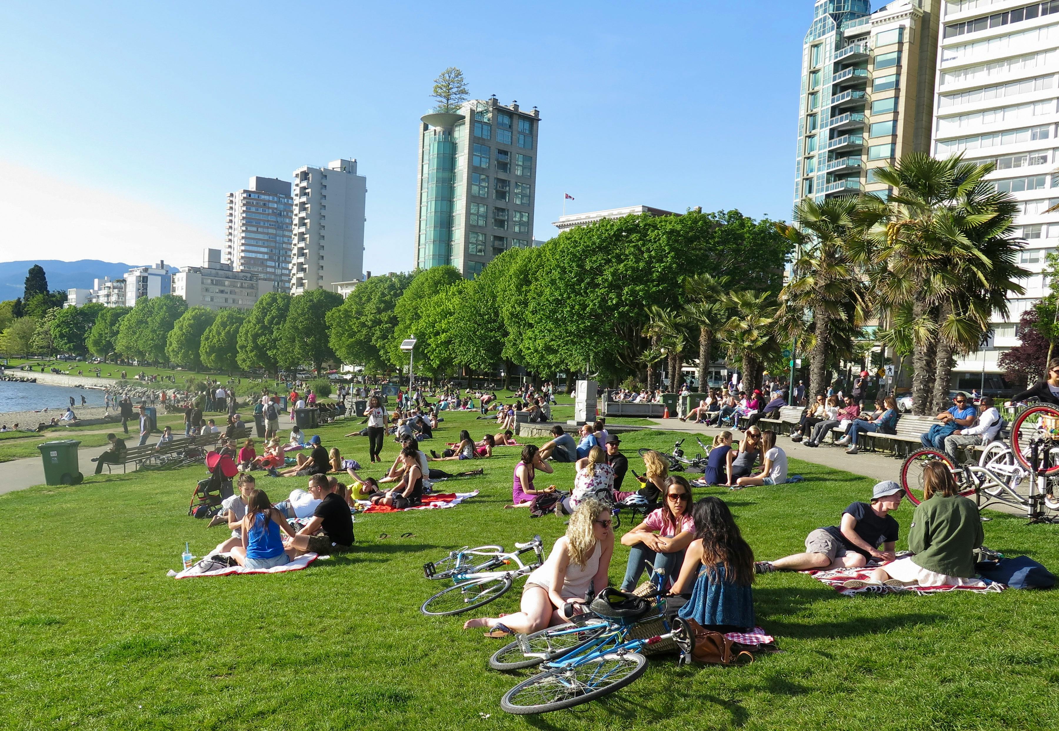 Locals relaxing on the grass at English Bay on a sunny day, enjoying cheap summer activities in Vancouver.