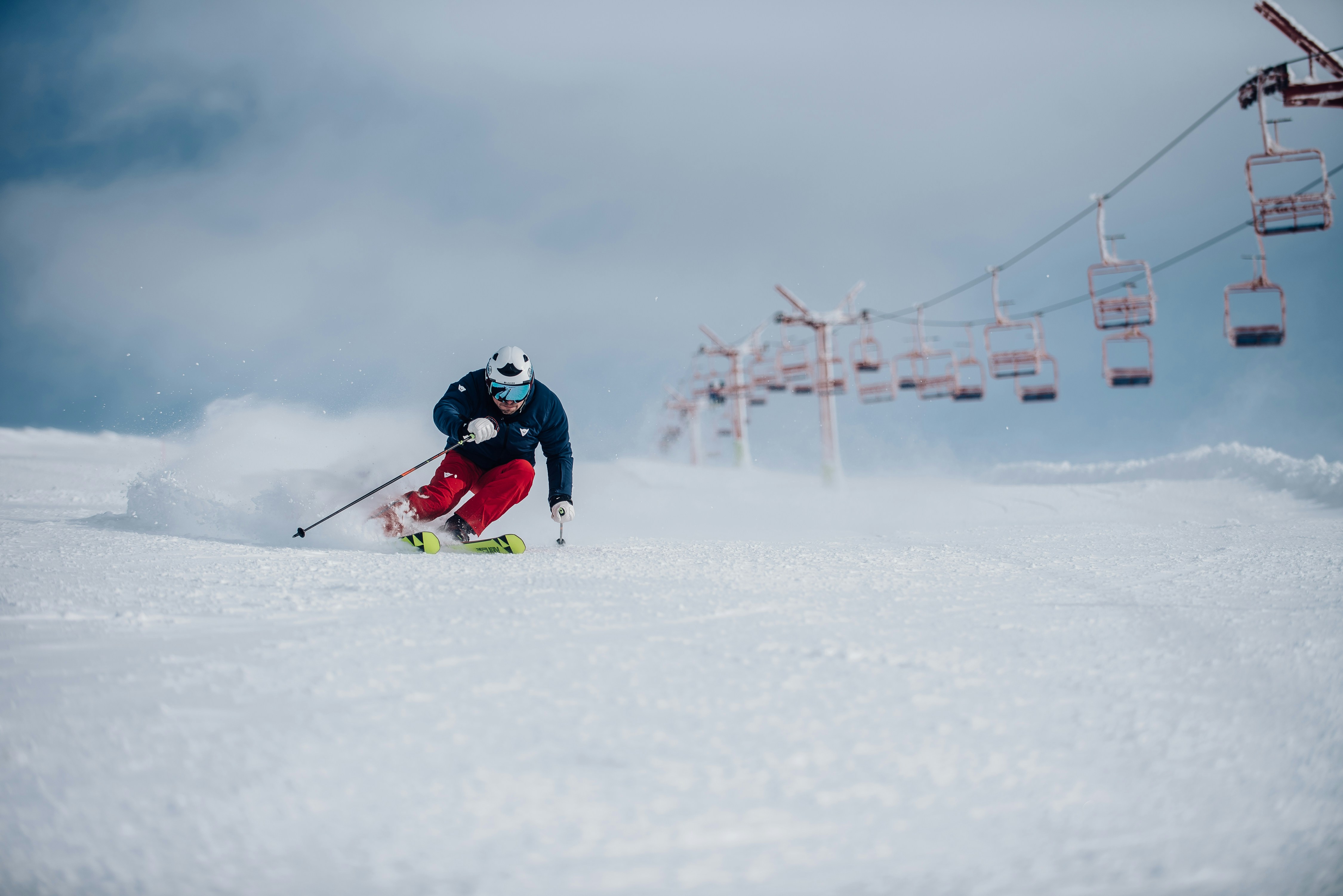 a person skiing down a snowy hill under a ski lift