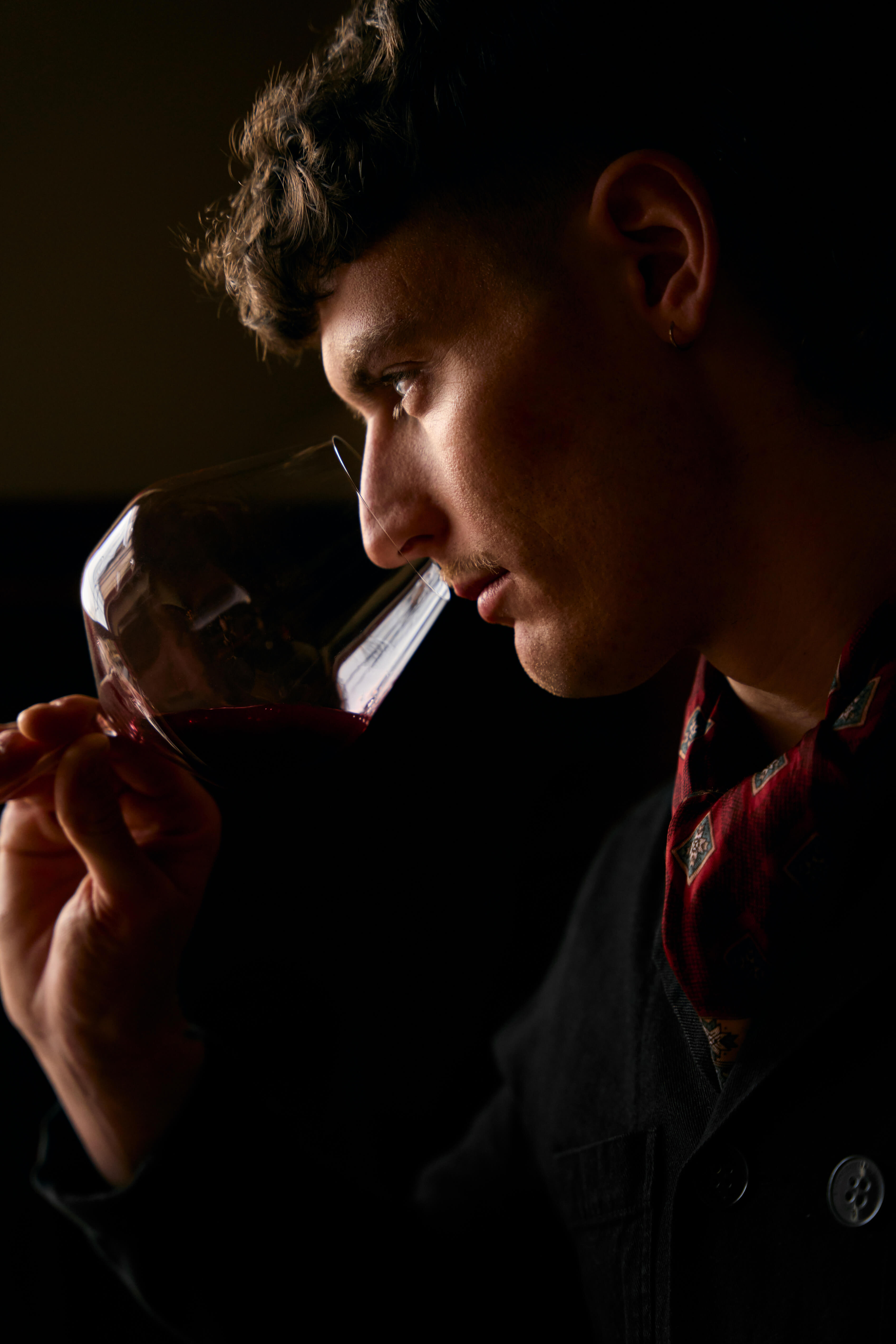 Close-up of a person smelling a wine glass in the warm restaurant lighting.