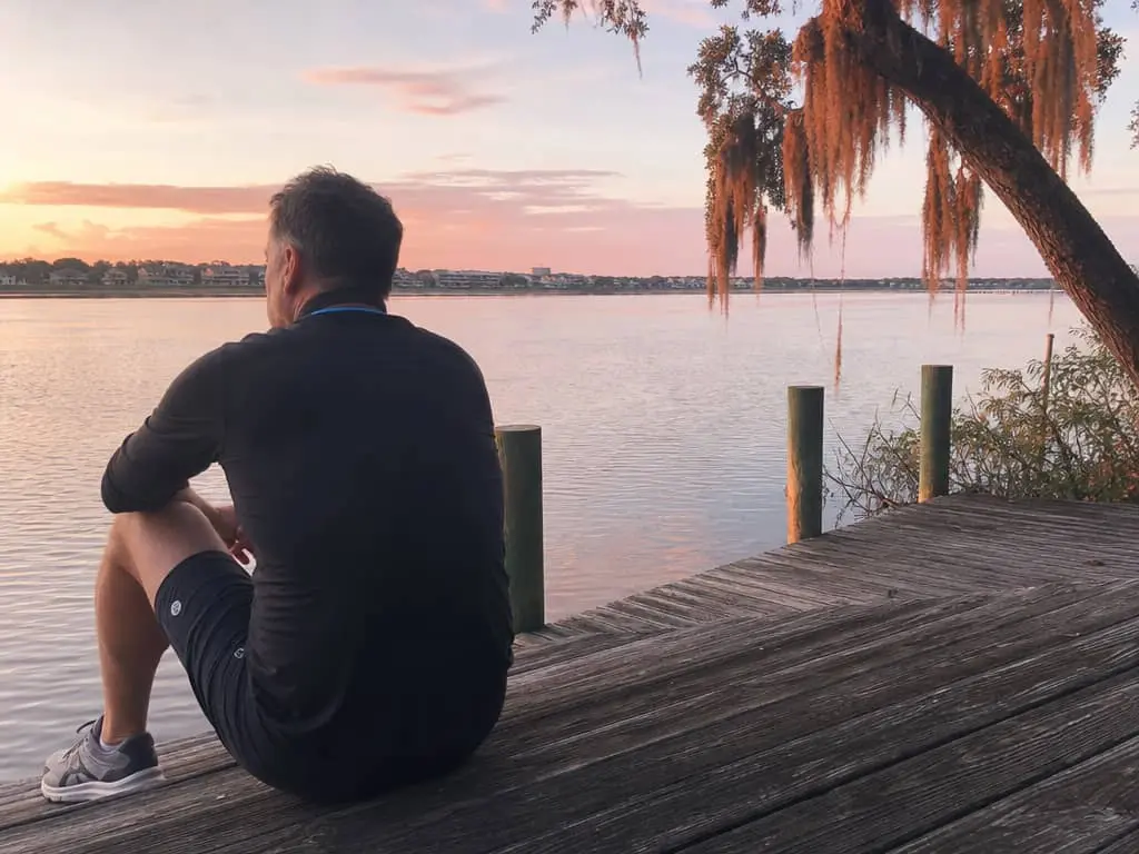 Man sitting on Charleston waterfront dock after a morning workout, looking out at the water — Peptide Therapy & Advanced Therapeutics at Hero Health & Hormone