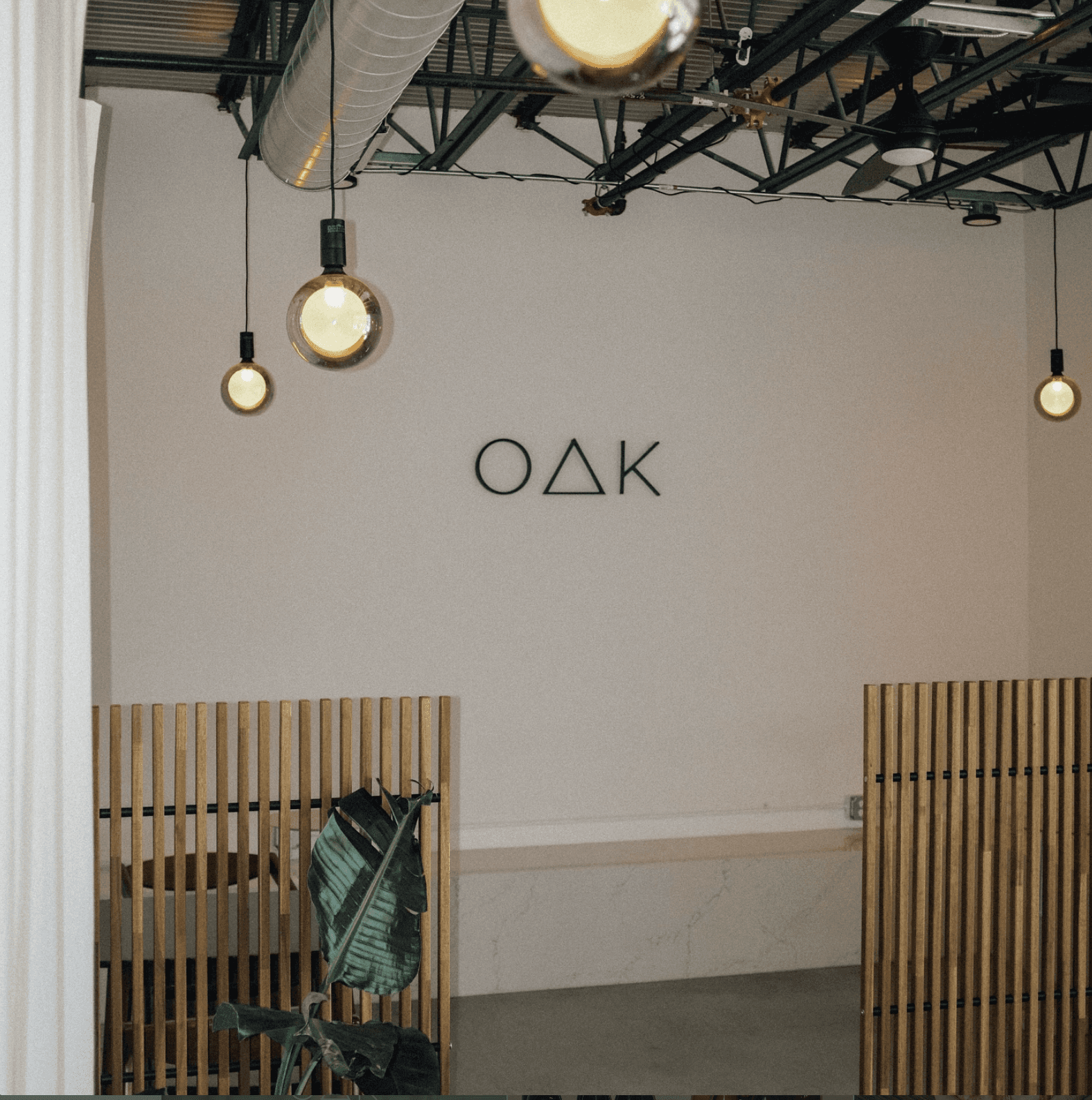 Minimal interior wall with OAK dimensional logo signage at Oak & Saint café and wine bar.