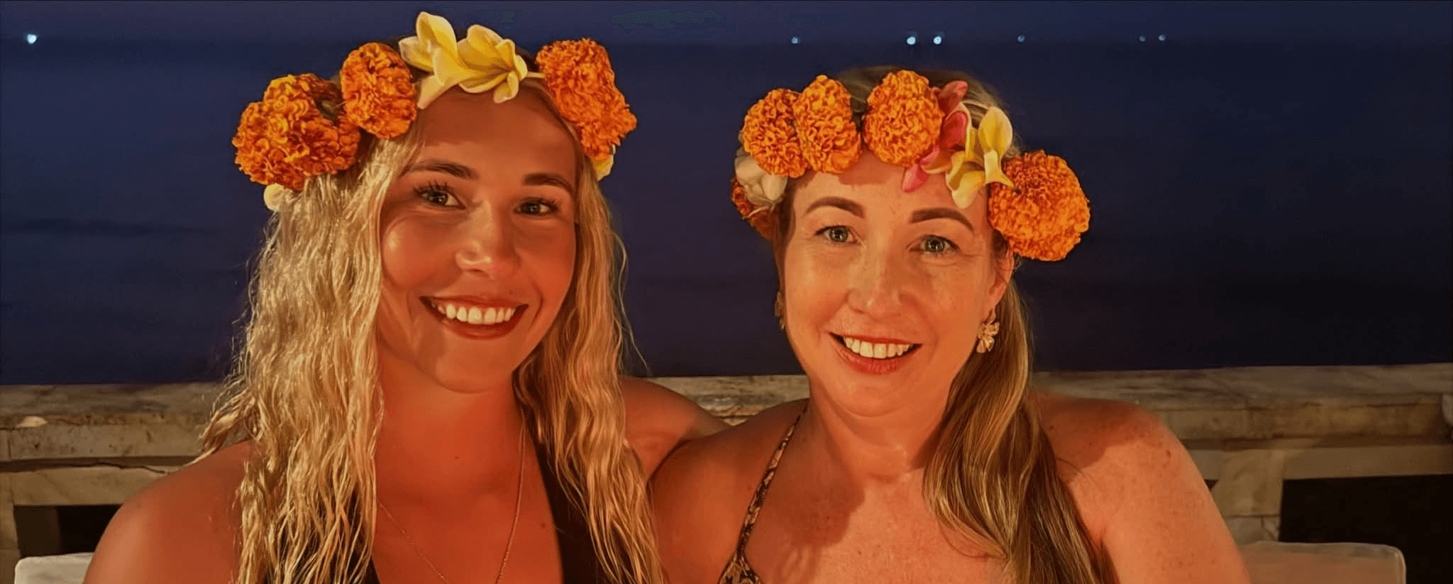 Mother and daughter wearing flower crowns in a tropical setting