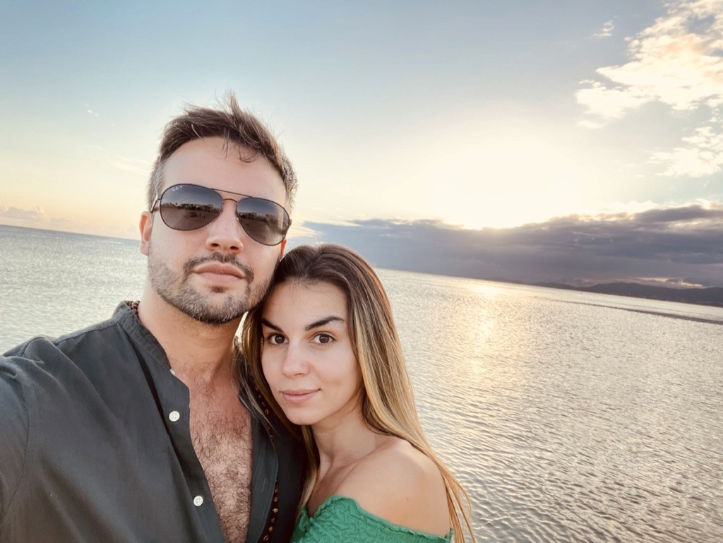 Close-up of two hands gently clasped, one wearing a sparkling engagement ring. The soft lighting and pastel nails evoke a sense of romance and intimacy.