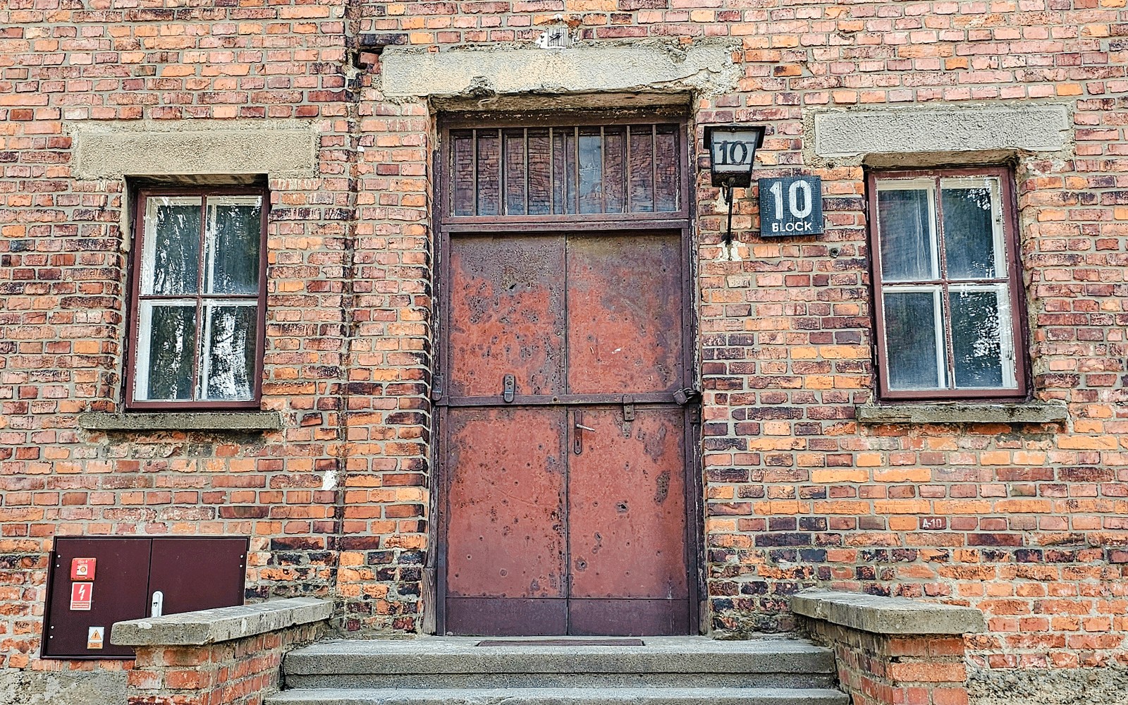 Entrada a los barracones en Auschwitz I, Bloque 10, con fachada de ladrillo y puerta metálica.