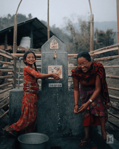 Photo of two people at a water source