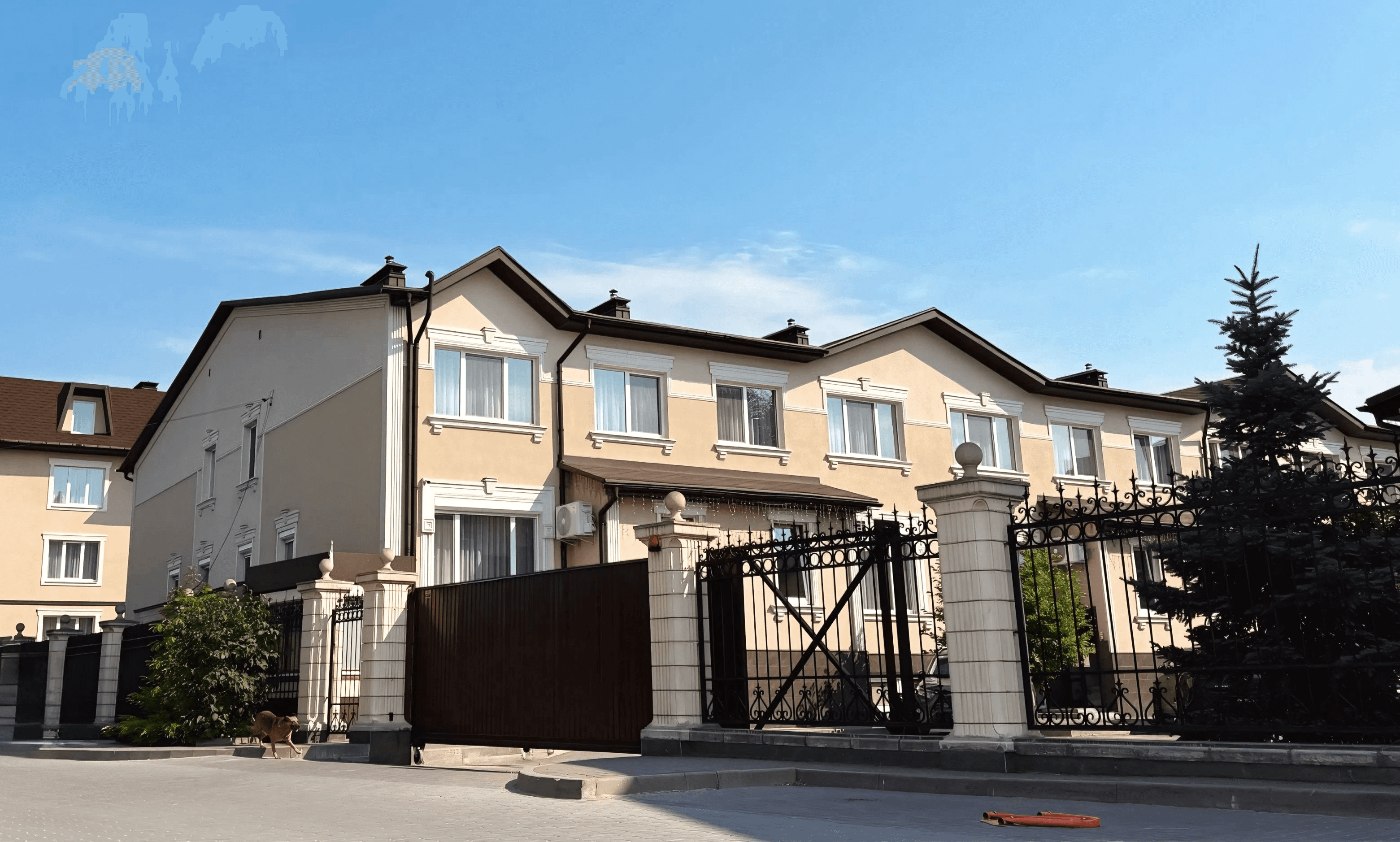 Двоповерховий таунхаус із контрастним дахом, білими віконними наличниками та кованою огорожею