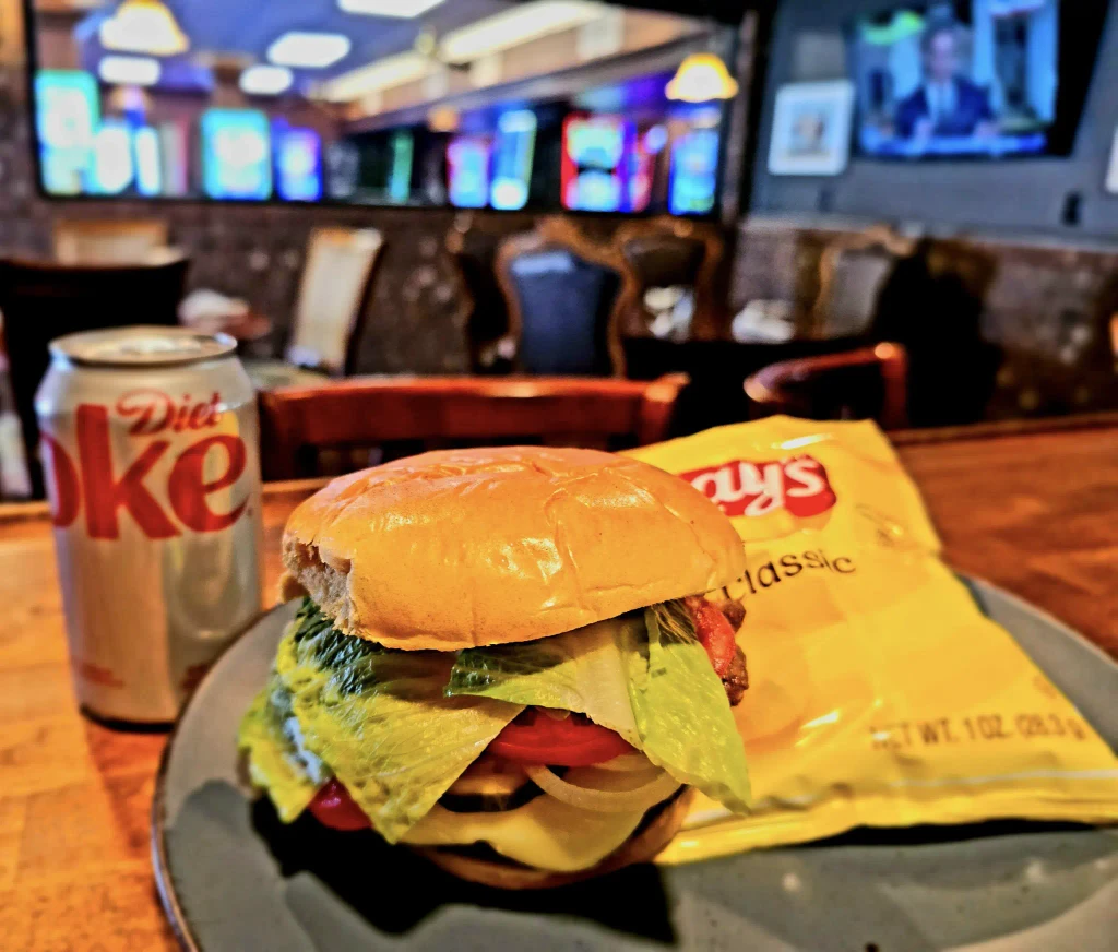 Classic American burger served with a side of crispy chips and a Diet Coke at Dueling Pistols restaurant in Adairville, KY.