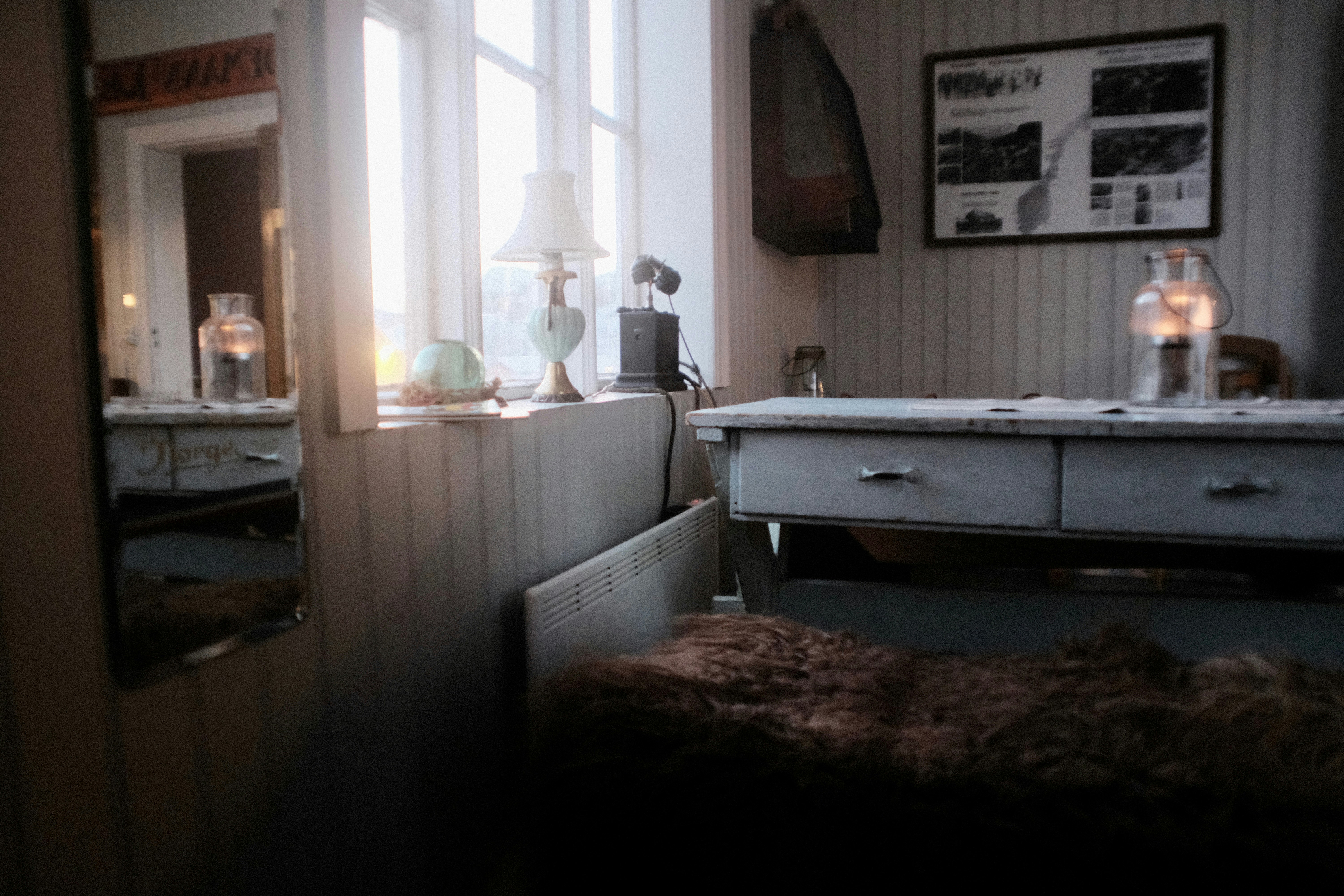 A room with a bed, dresser and a window