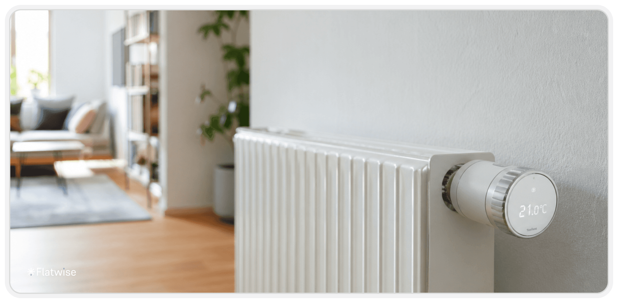 Modernes Wohnzimmer mit hellem Holzboden und einem weißen Heizkörper im Vordergrund, an dem ein smartes Thermostat mit digitaler Temperaturanzeige angebracht ist.