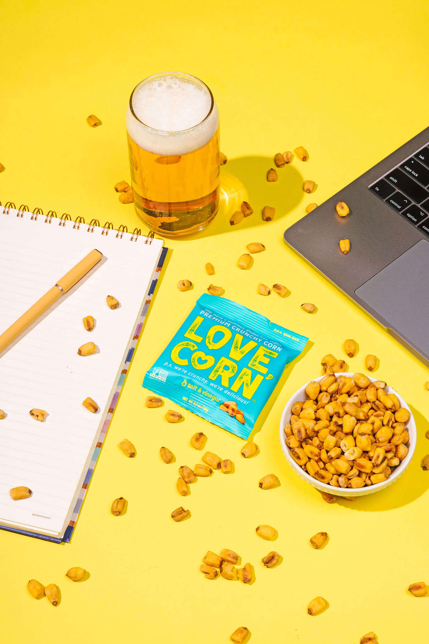 blue plastic pack of love corn on yellow table with snacks and beer