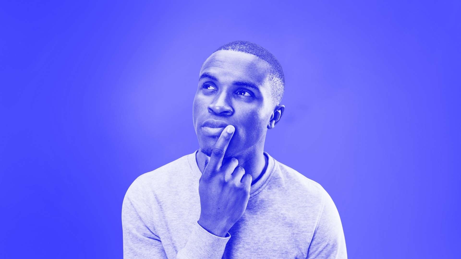 Man looking pensive with his index finge on the corner of his mouth