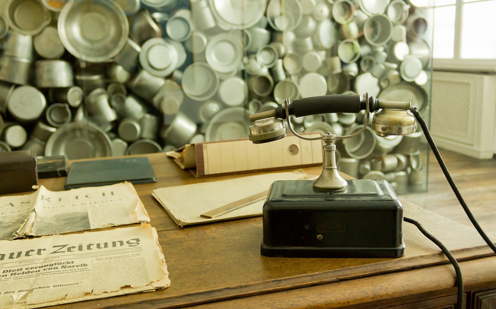 Antiguo teléfono y periódicos en la exhibición de la Fábrica de Oskar Schindler en Cracovia.