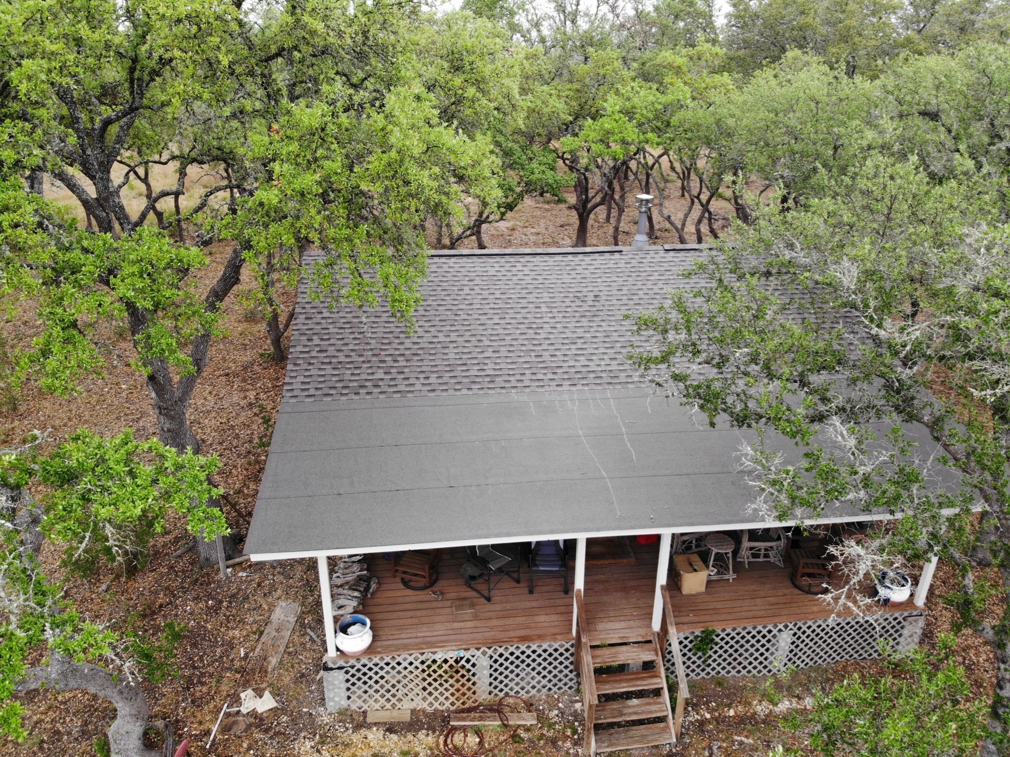 Small hunting lodge in Dripping Springs with a gable roof featuring architectural shingles and a modified bitumen porch, blending rustic charm with durability.