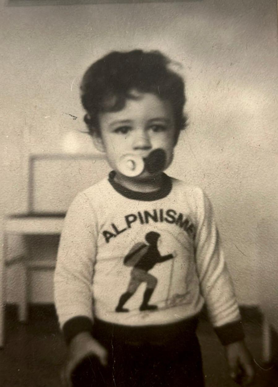 fotografía antigua de niño con chupa y una camiseta blanca que pone alpinismo