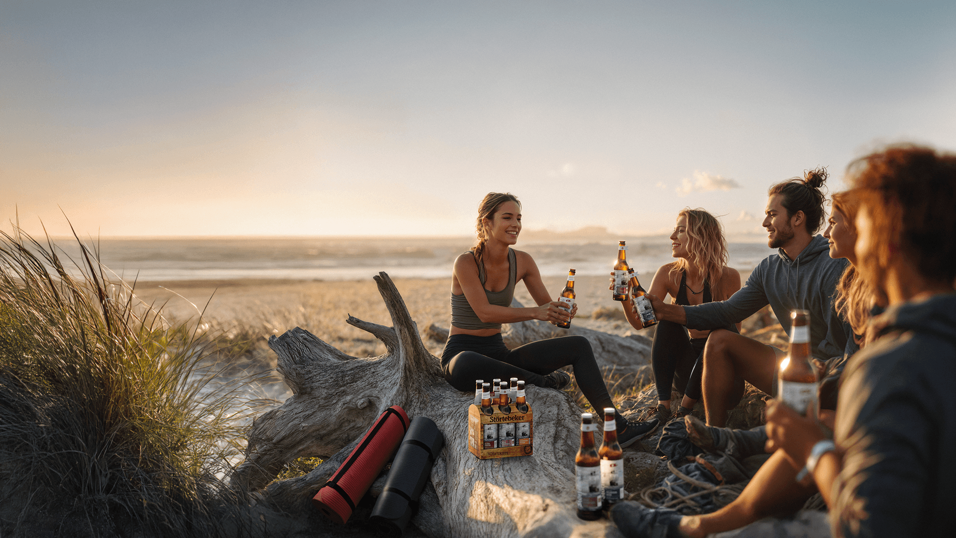 Friends toasting with beer on a beach at sunset