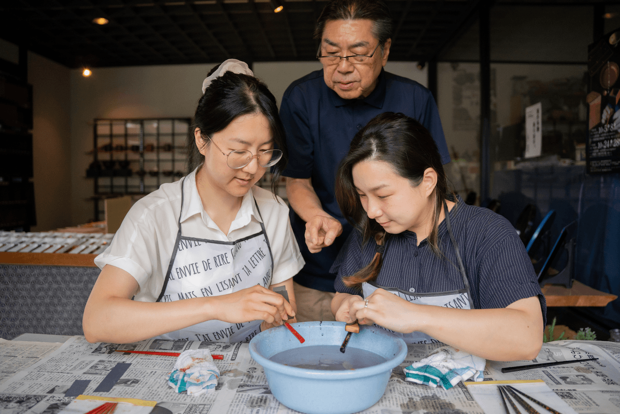 Craftsman guiding students on making lacquerware chopsticks