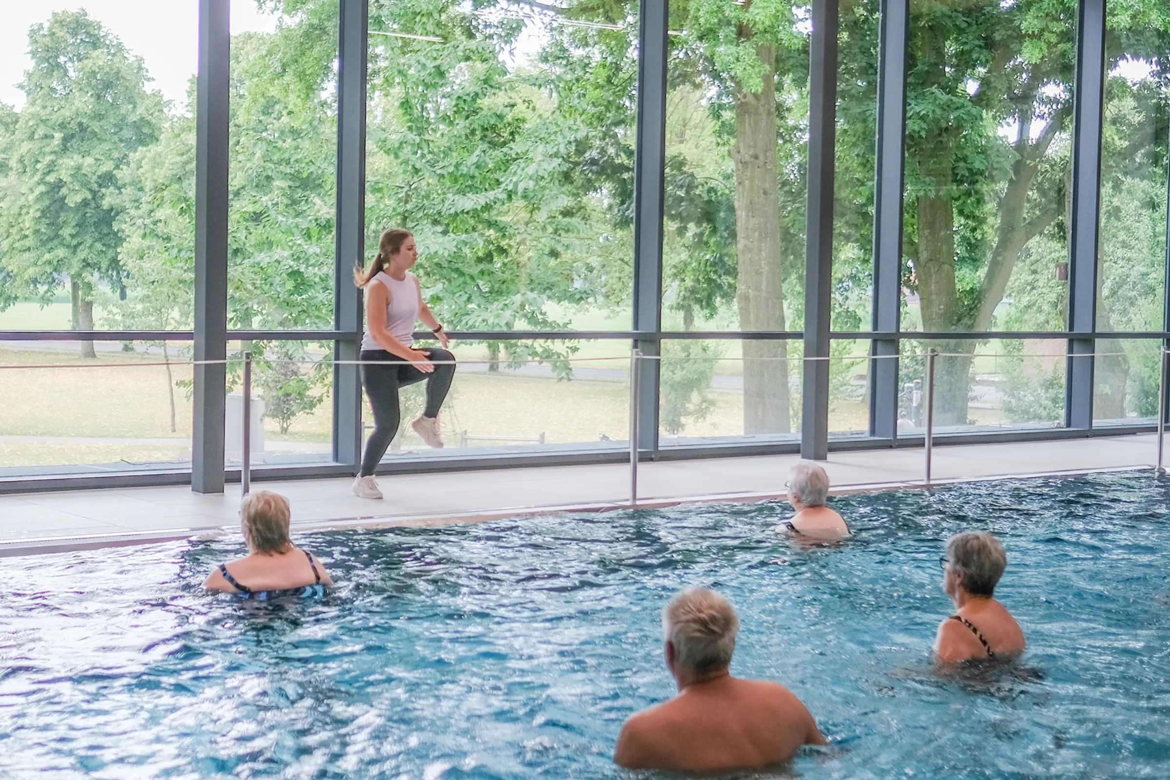 Aquafitness-Kurleitung Silke Janßen leitet Gruppe von Menschen im Wasser an