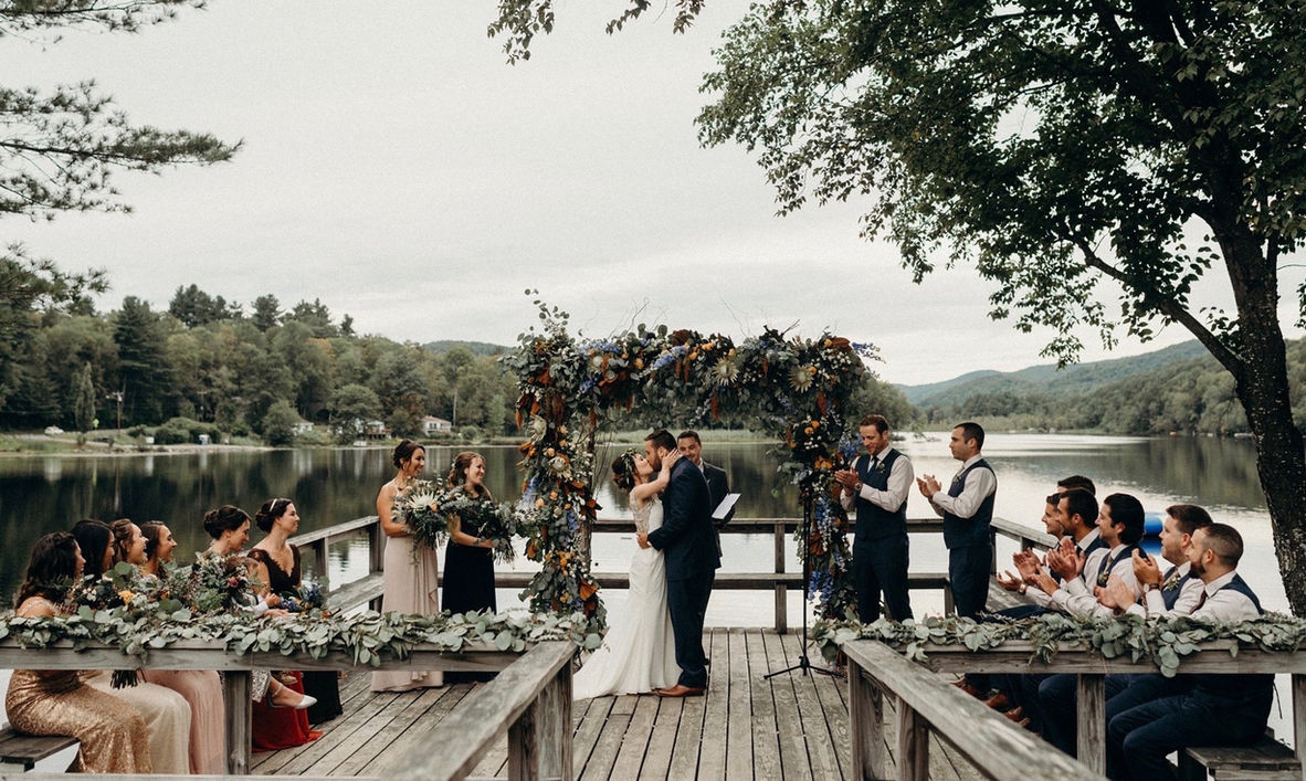 Couple kissing at a lakeside wedding ceremony at Camp Lenox