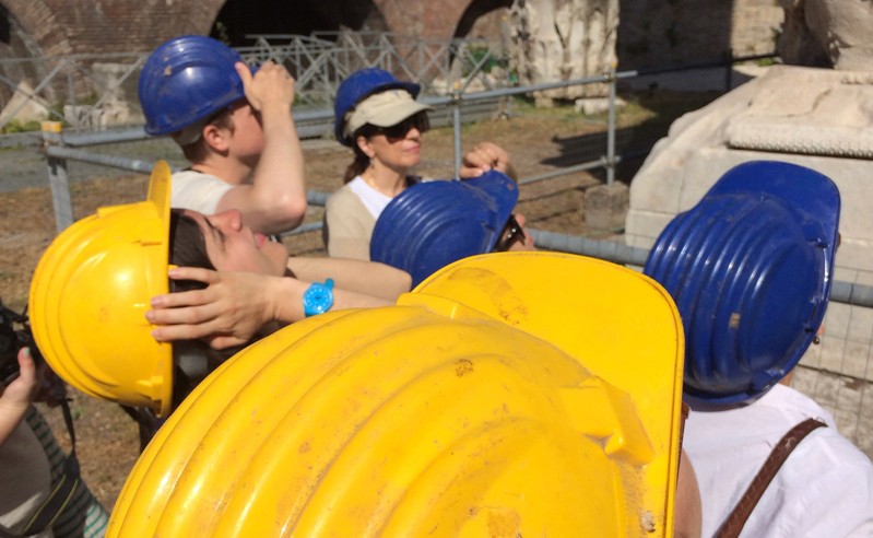 A photo of people visiting a construction site and wearing yellow and blue protective hats.