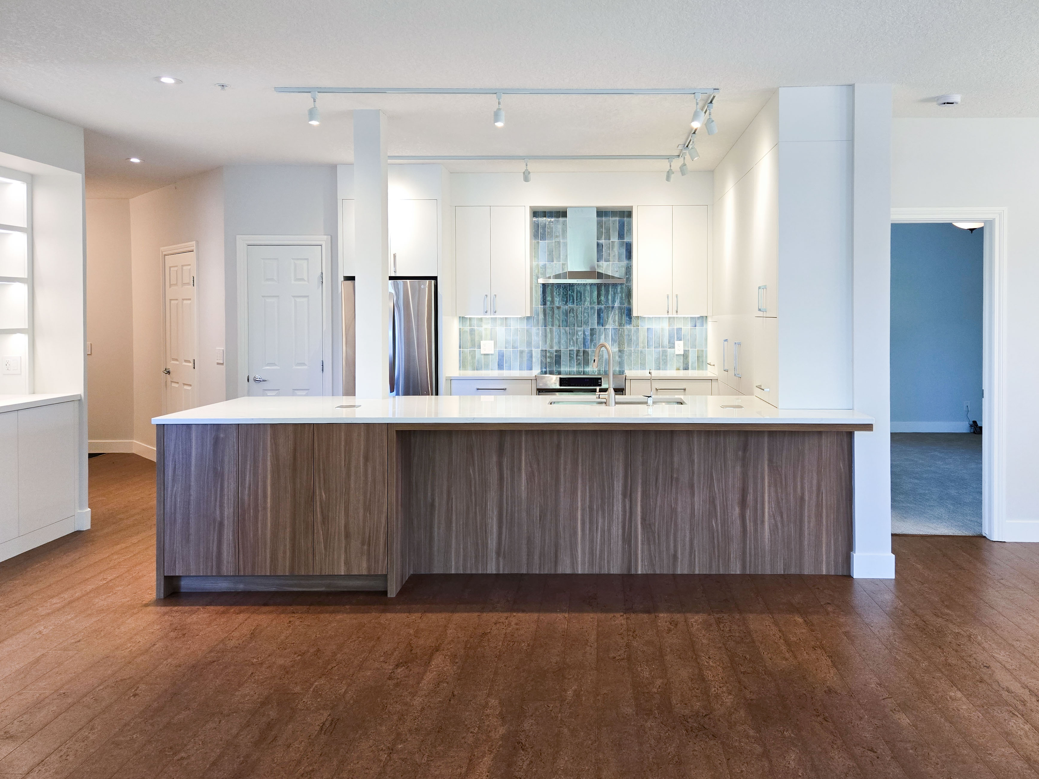 Image of Modern kitchen with large island, white countertops, and blue tile backsplash by KHD Homes design-build.