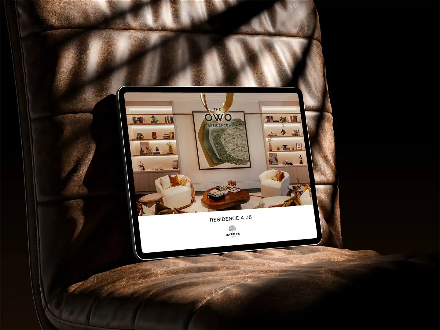 Tablet resting on a premium leather chair displaying an interior from The OWO Residences marketing materials.