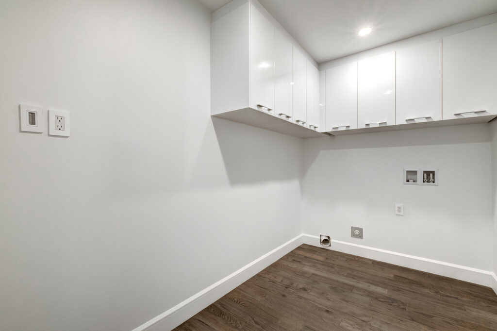Sleek condo laundry room renovation by B&Y Reno Corp, showcasing glossy white upper cabinetry and space-saving layout designed for compact urban living