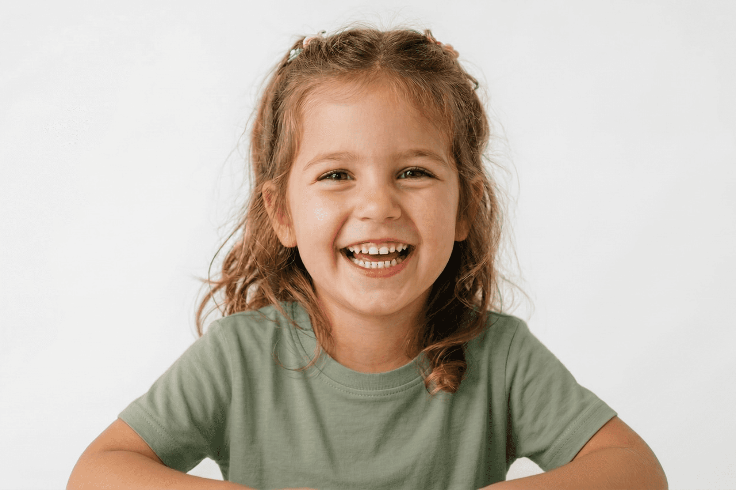 A happy young girl with a broad smile and hair tied back, representing gentle pediatric dental care at Bolton Kids Dental.