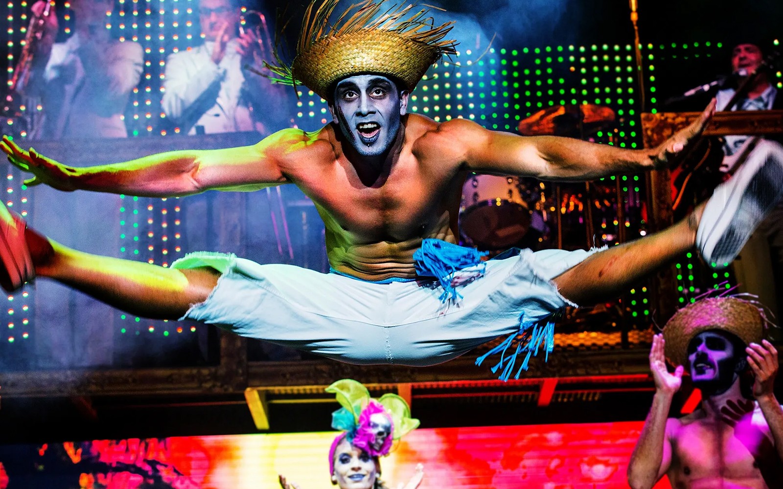 在充满活力的舞台灯光下，表演者在僵尸滑稽秀中表演空中劈腿。