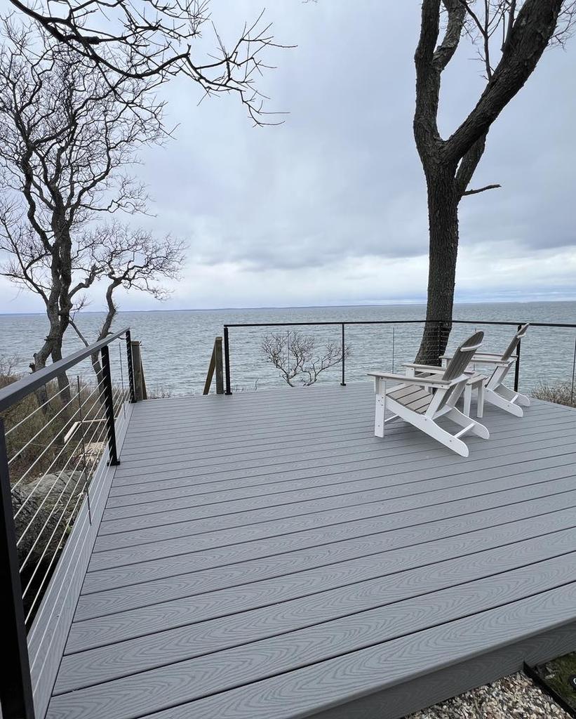Gray composite deck with black cable railing above a rocky shoreline