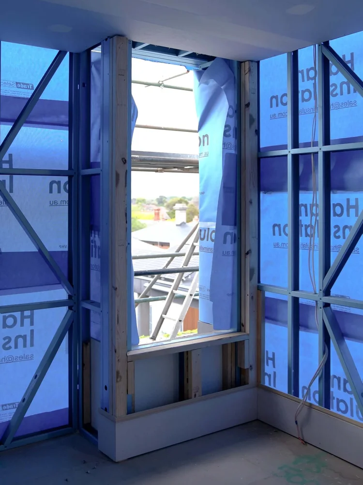 Residential building under construction with scaffolding and insulation visible.