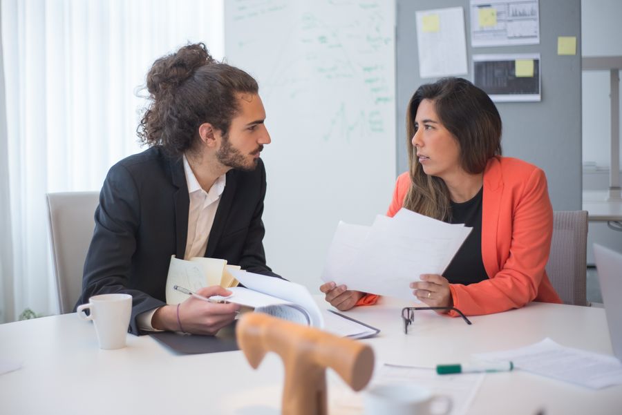 Two colleagues in a focused one-on-one discussion across an office table
