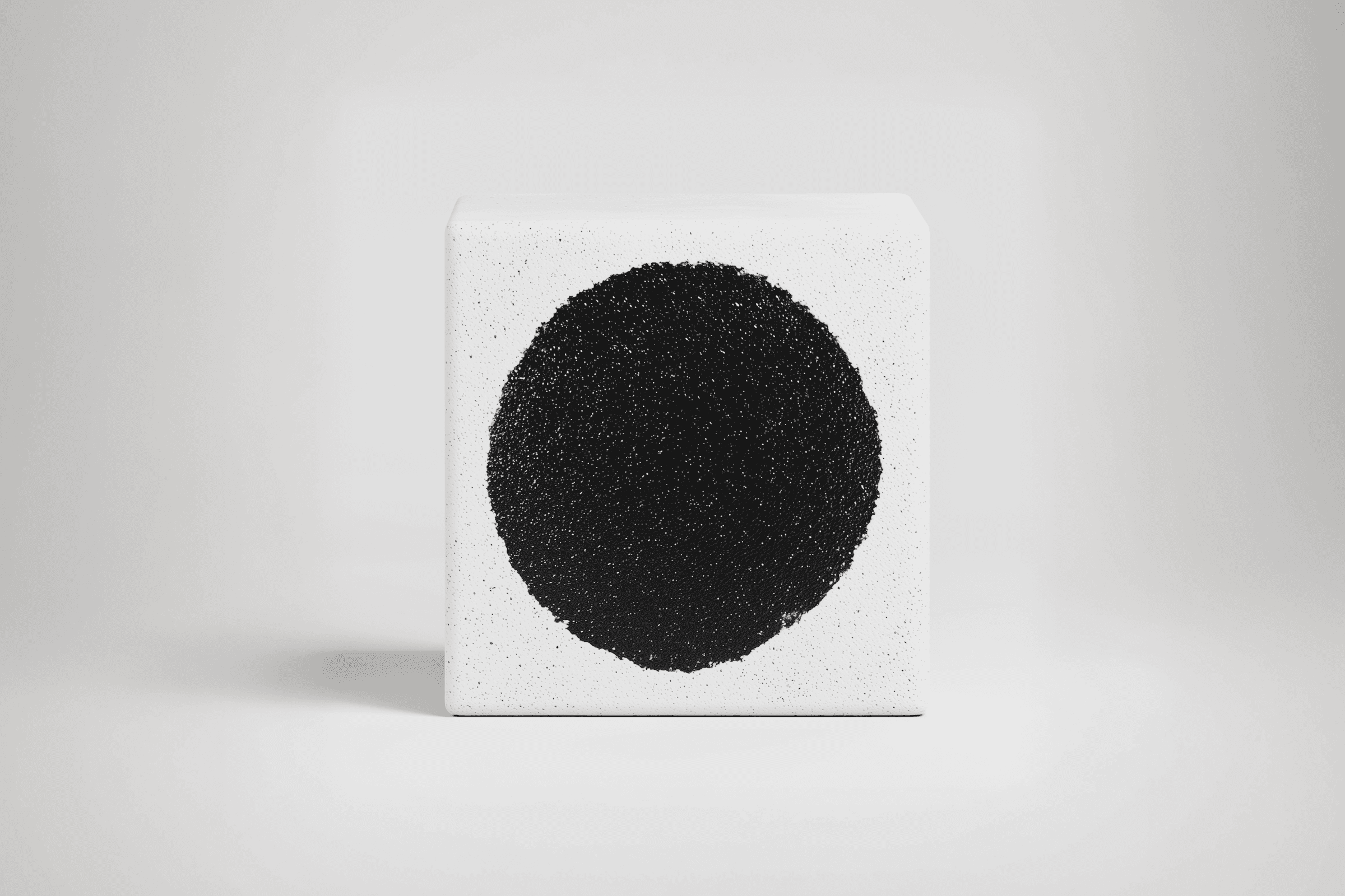 Minimalist white cube with a bold black circle, featuring a textured surface and sharp edges, creating a striking geometric contrast.