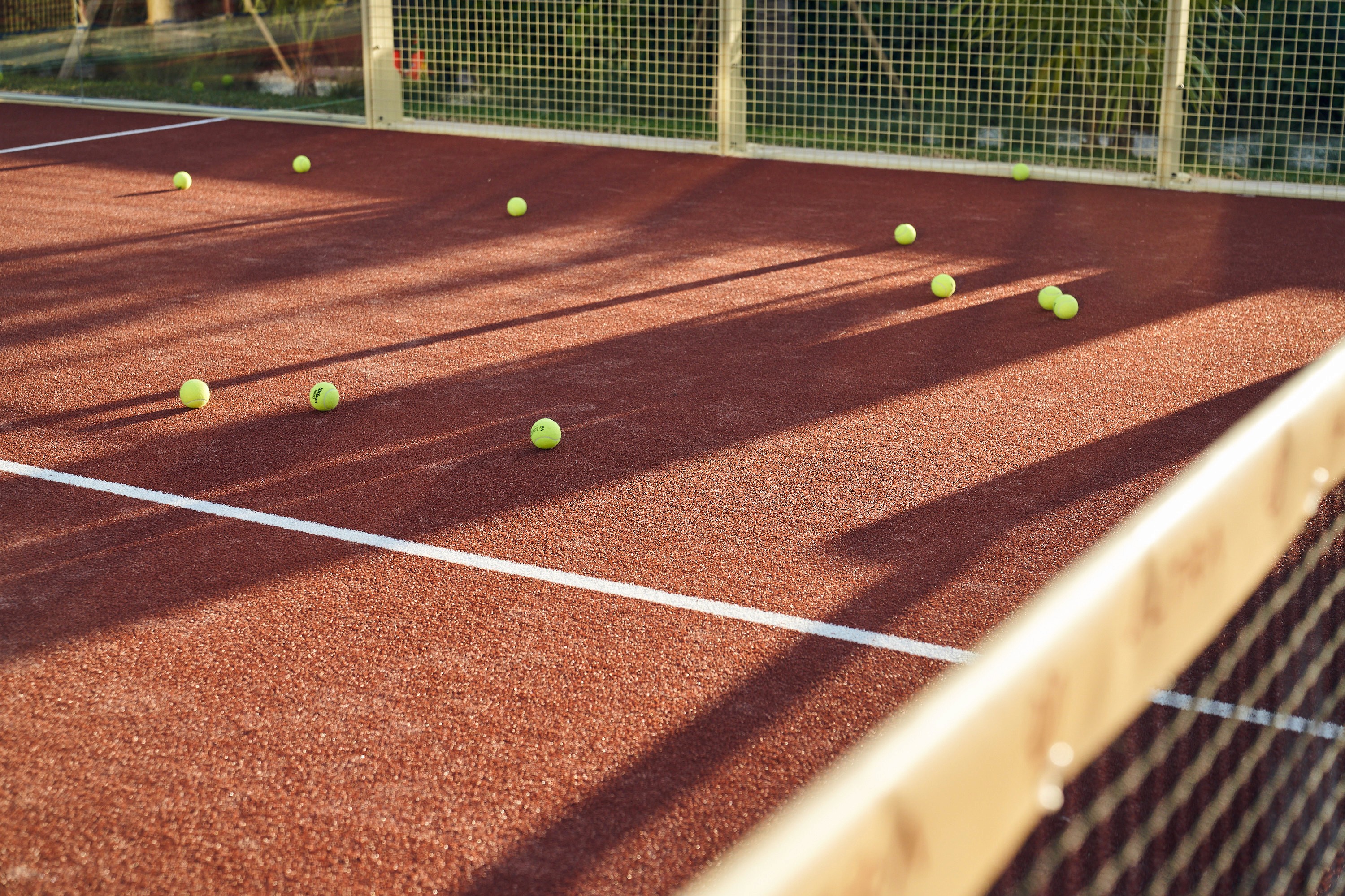 tennis balls on red padel court